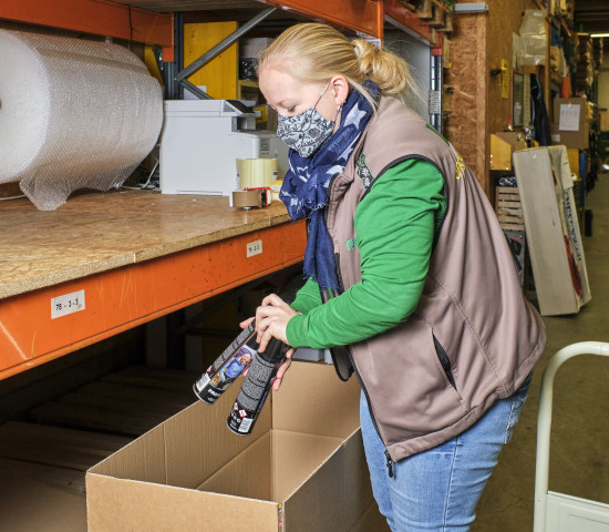 Eine Mitarbeiterin verpackt Produkte zum Versand im Lager eines Landi-Ladens.