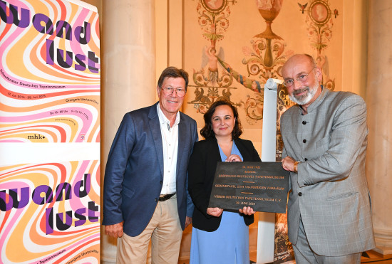 Ullrich Eitel, Vorsitzender des Tapetenmuseums überreicht Staatssekretärin Ayse Asar und Prof. Dr. Martin Eberle, Direktor von Hessen Kassel Heritage, die Bronzetafel zum Jubiläum für den Neubau des Tapetenmuseums.