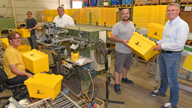 Die Siebdruckmaschine bedient Andreas Knoblach (links), seine Kollegen Matthias Weyell (2 v. l.) und Sebastian Meißner (2. v. r.) stellen die Boxen aufs Rollband und die Paletten.